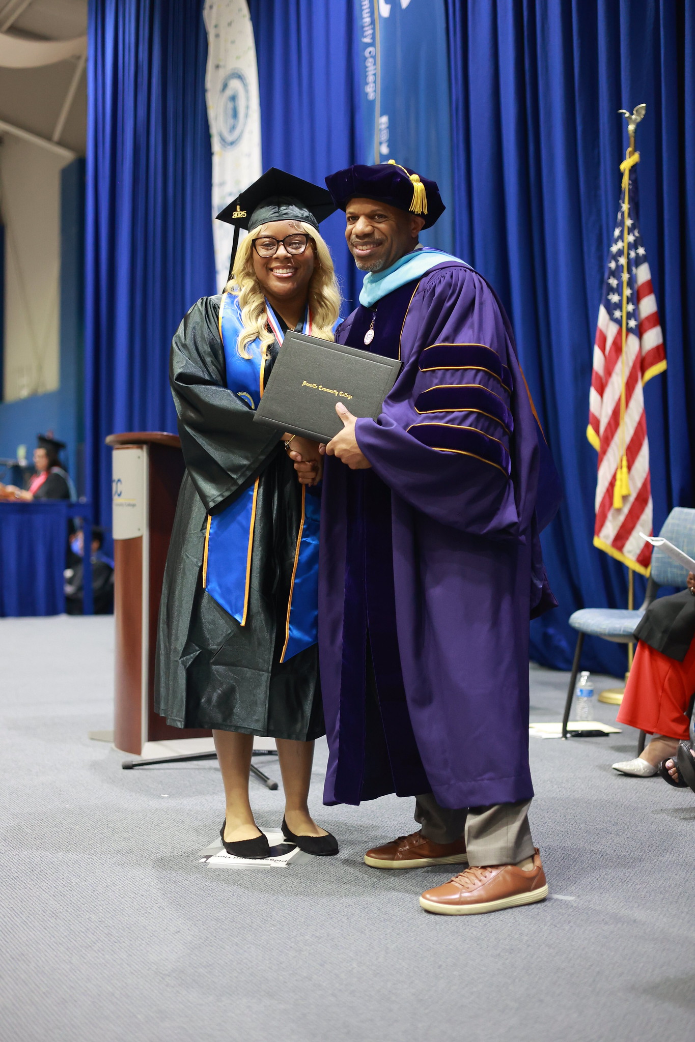 Student at graduation shaking hands with the college president