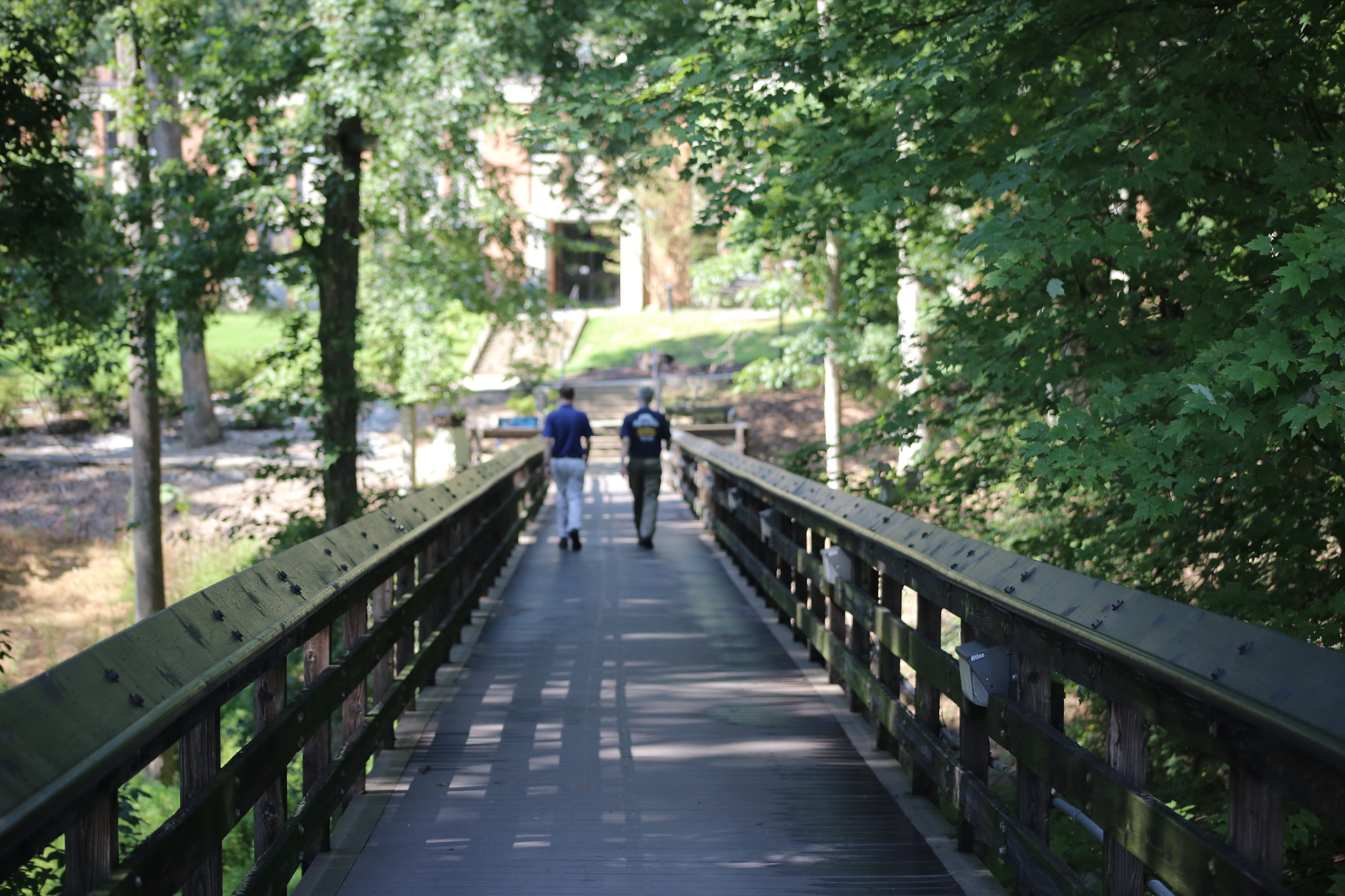 Two people walking across a bridge