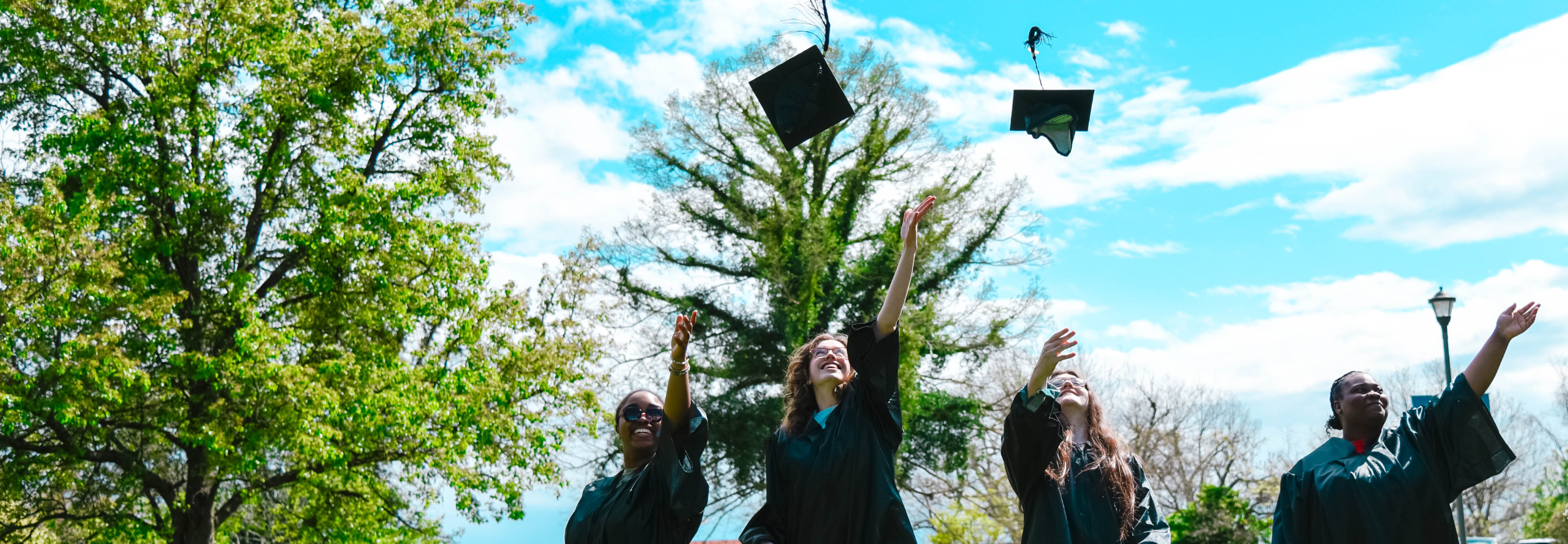 students throwing graduation caps up into the sky. 
